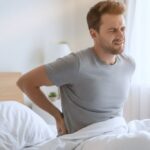 Middle-aged man experiencing chronic lower back pain due to an underlying spinal condition requiring medical evaluation.