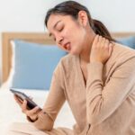 Woman experiencing neck pain and tingling sensations in her hands due to cervical nerve compression.