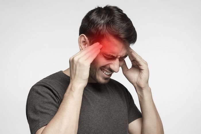 Man experiencing persistent headaches after a head injury, highlighting the importance of neurological evaluation following an accident.
